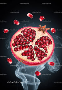 Fresh pomegranate half with seeds floating in smoke