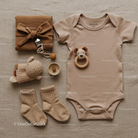 Neutral toned baby essentials laid out on fabric background