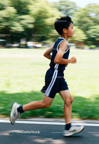 Young boy running fast in park on sunny day
