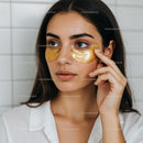 Young Woman Applying Gold Eye Patches for Skin Rejuvenation