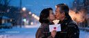Couple sharing a tender kiss with a love letter in winter