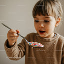 Curious Child Holding Spoon with Colorful Sprinkles