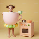 Little girl dressed as giant pink teacup playing kitchen