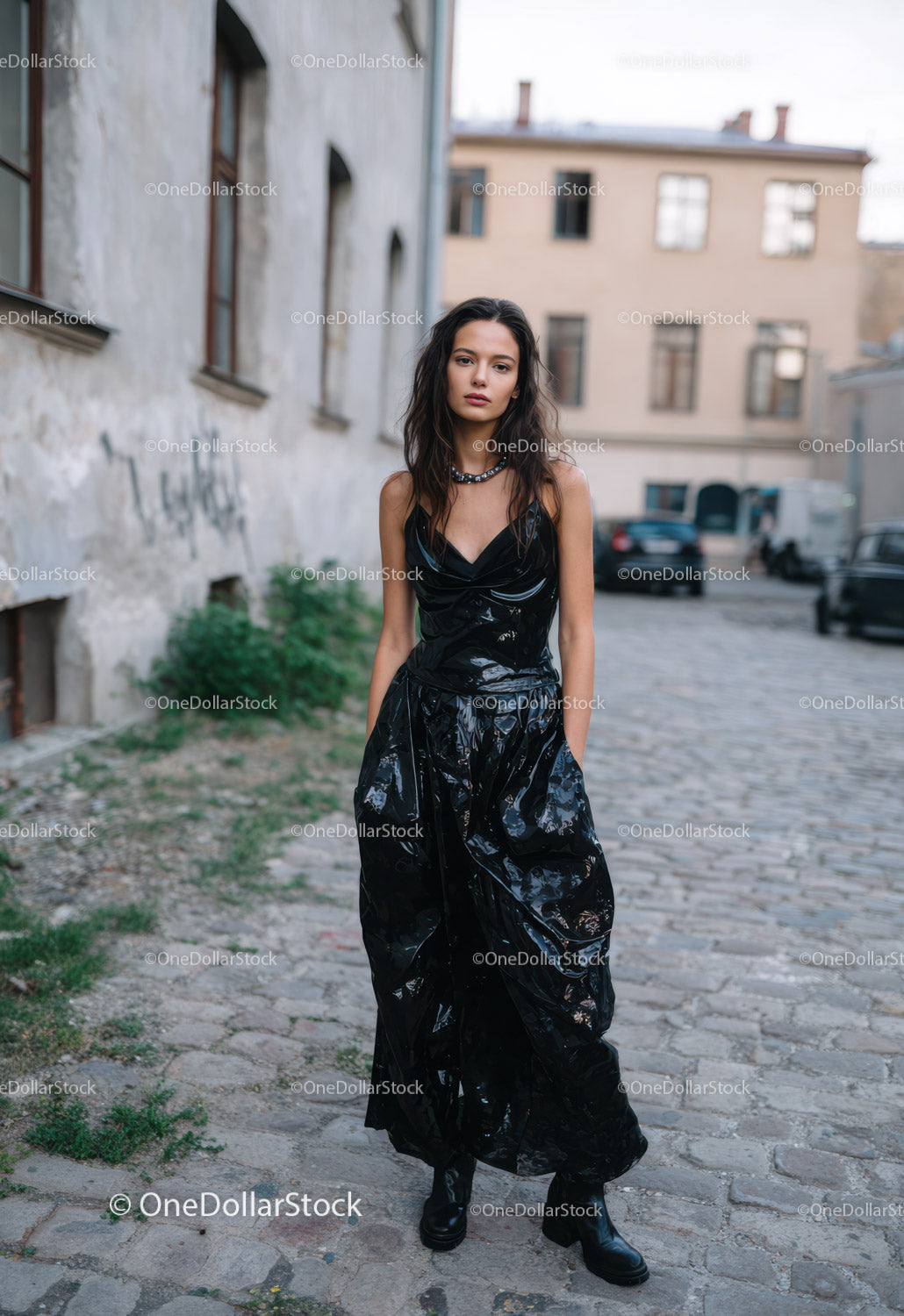 Fashionable Woman in Vinyl Outfit Walking on Urban Cobblestone Street