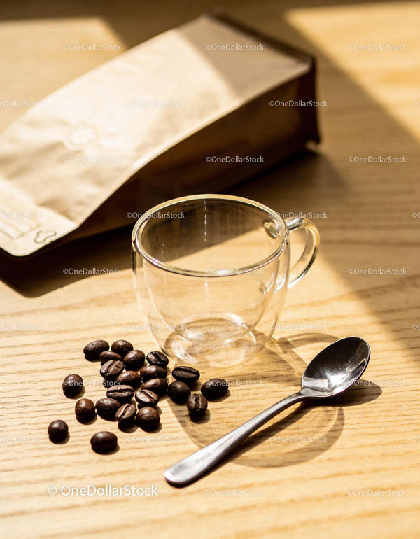 Clear glass cup and coffee beans in warm sunlight