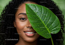 Smiling Woman with Curly Hair Holding Large Green Leaf Amid Lush Foliage