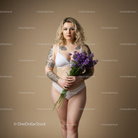Portrait of a Tattooed Woman Holding Purple Flowers in Lingerie Studio