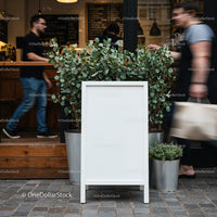 Blank outdoor menu board with potted plants in cafe entrance
