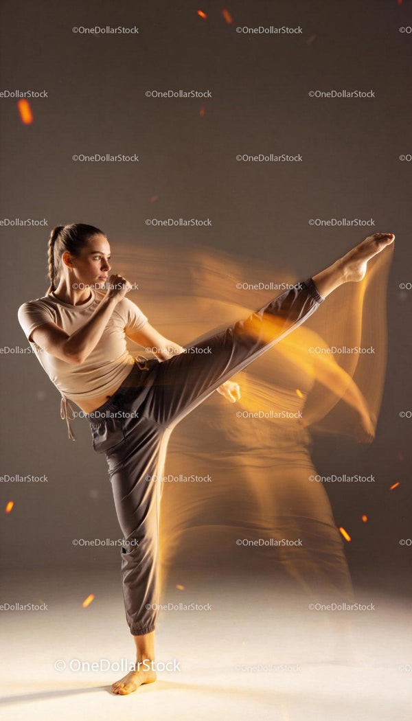 Focused woman practicing dynamic martial arts kick