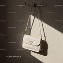 Minimalist white leather purse hanging on wall hook