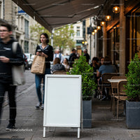 Blank white signboard on busy city cafe sidewalk