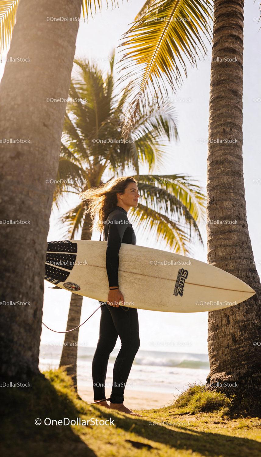 Woman Surfer Standing on Sunny Tropical Beach with Board