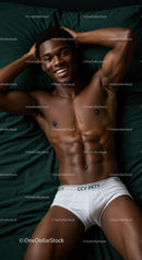 Smiling young man relaxing on bed in white briefs