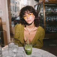 Stylish Young Woman with Yellow Glasses and Green Drink in Cafe