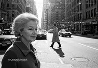 Elderly Woman in Busy City Street Surrounded by Vintage Cars