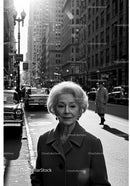 Elegant Elderly Woman in Coat Walking on City Street in Black and White