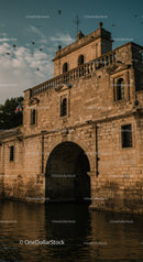 Historic stone fortress archway over calm water at sunset