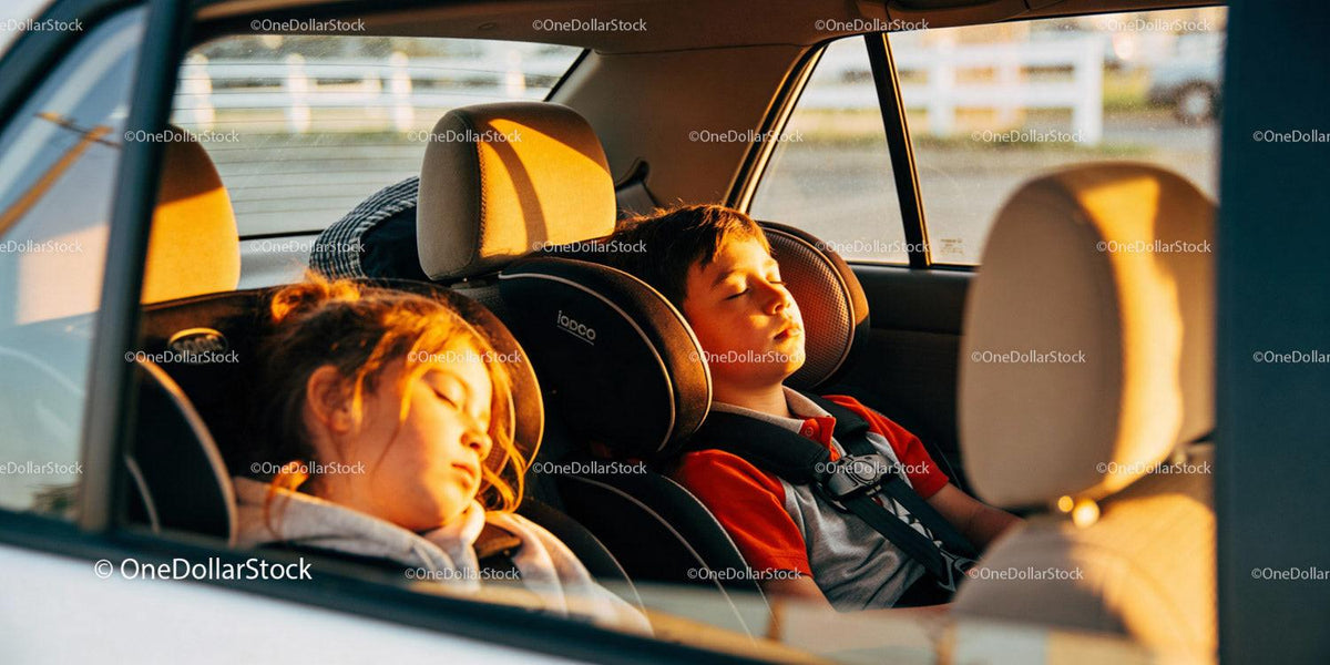 Children peacefully sleeping in car seats at sunset