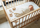 Peaceful newborn swaddled in soft blanket in wooden crib