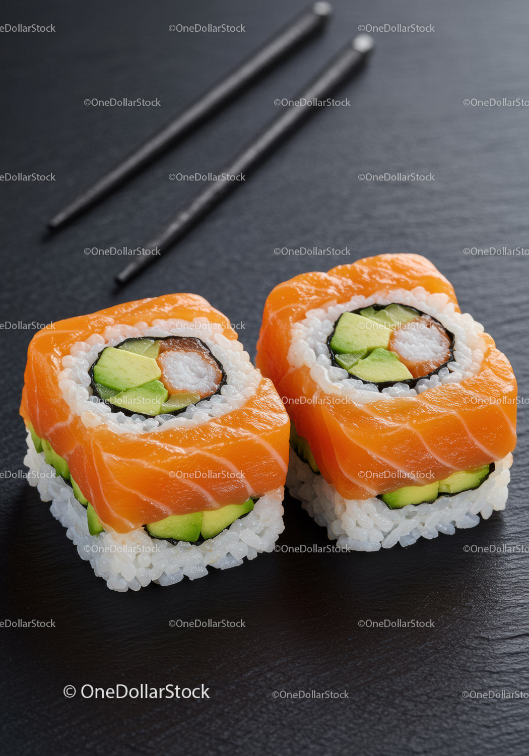 Fresh salmon avocado sushi rolls on black slate