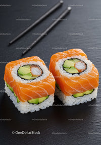 Fresh salmon avocado sushi rolls on black slate