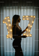Silhouette of young woman holding glowing number balloons