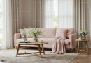Cozy living room with soft pink sofa and floral decor