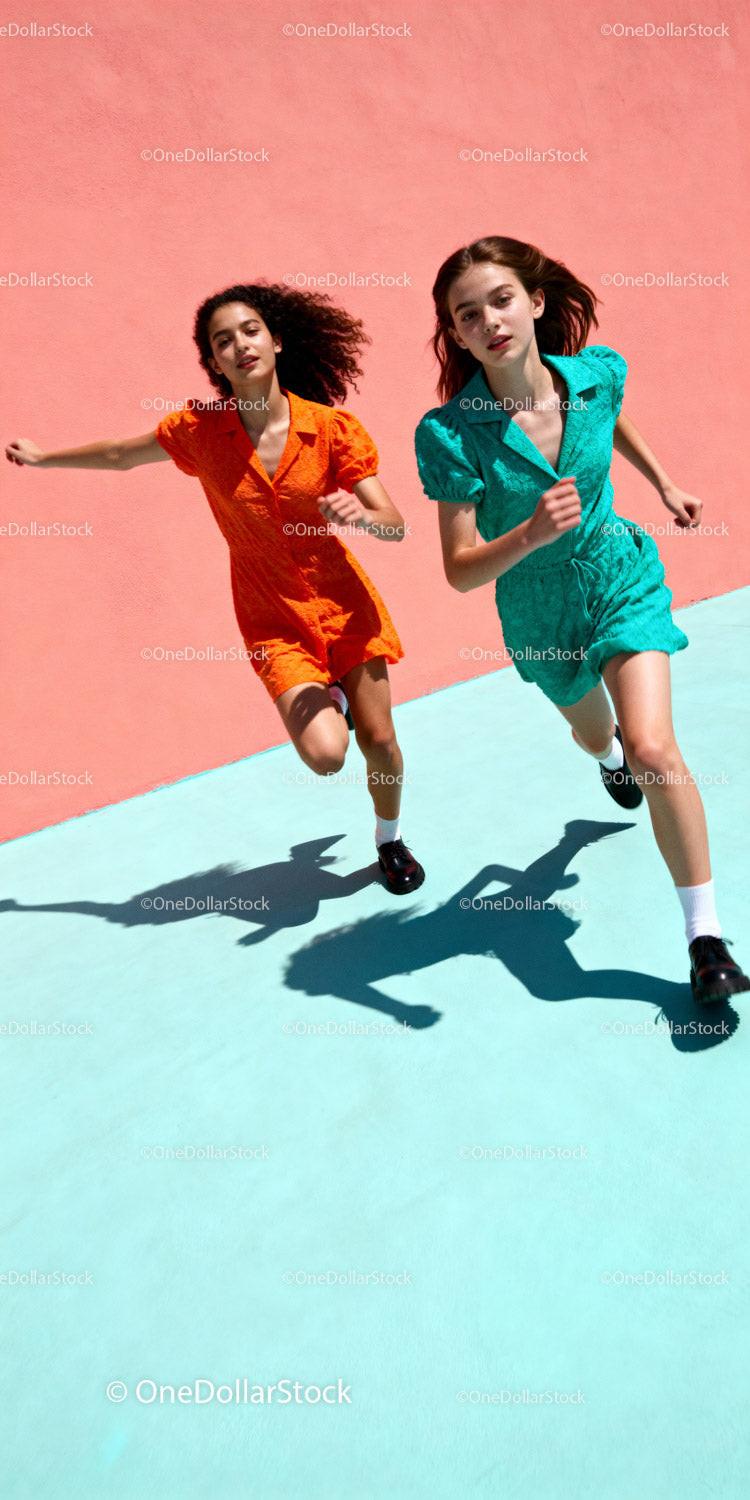 Two Young Women Running Against Vibrant Color Background