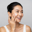 Smiling Woman Applying Moisturizer with Glowing Skin