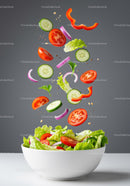 Fresh vegetable salad ingredients suspended above bowl