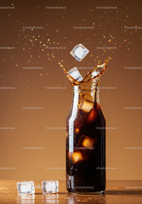 Refreshing cola splash with ice cubes in glass bottle