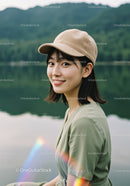Young Woman in Green Dress Wearing Beige Cap Near Lake Landscape