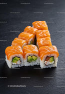 Fresh salmon sushi rolls with avocado on dark surface