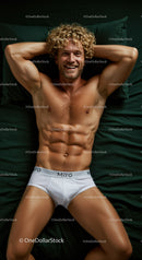 Smiling fit man relaxing on dark green bed in white briefs