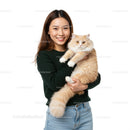 Smiling woman holding fluffy cream cat indoors
