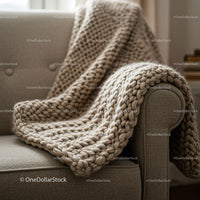Cozy chunky knit blanket draped on gray sofa armrest