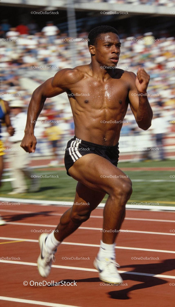 Focused male sprinter racing intensely on a sunny track