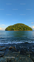 Tropical Green Island with Rocky Shoreline in Calm Blue Sea