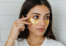 Young Woman Applying Gold Under-Eye Patches for Skin Care