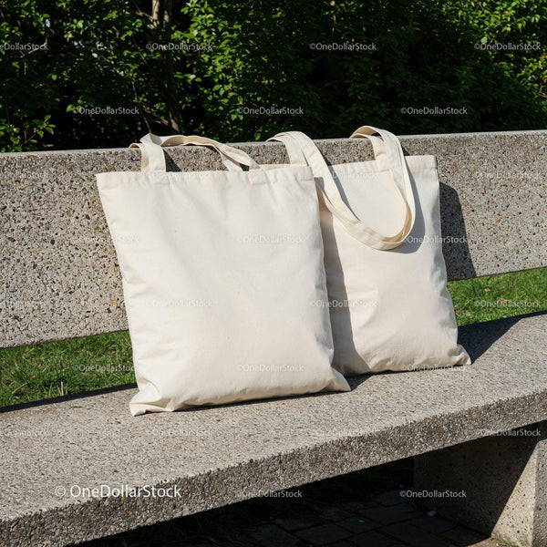 Two blank canvas tote bags on stone park bench JPG Mockup Image