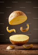 Fresh potato sliced with peeling in midair on wooden surface