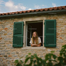 Smiling Woman by a Rustic Window with Green Shutters
