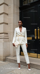 Confident woman in chic white pantsuit standing outdoors