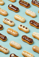Variety of decorated éclairs on pastel blue background