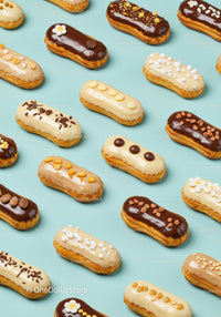Variety of decorated éclairs on pastel blue background