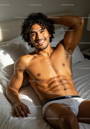Smiling man relaxing shirtless on bed in natural light