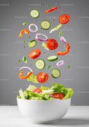 Fresh vegetable salad ingredients falling into bowl