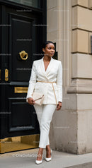 Confident woman in white suit standing near elegant black door