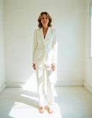 Elegant Woman in White Suit Standing in Bright Minimalist Room