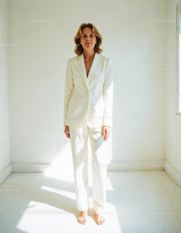 Elegant Woman in White Suit Standing in Bright Minimalist Room